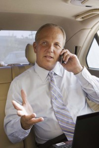 businessman in back-seat of car, using phone, gesturing with hand